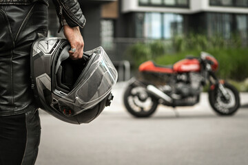 person holding helmet with motorcycle in background