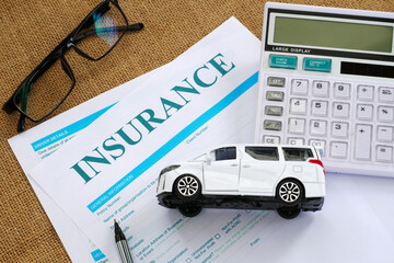 insurance settlement with toy car, glasses, and calculator