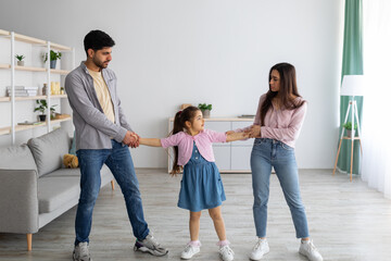 mother and father holding arms of child between them