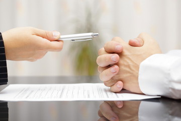 person handing another person a pen over divorce papers