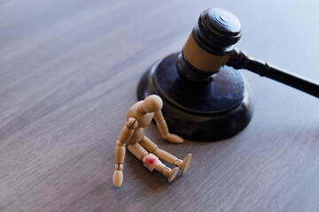 wooden doll with bloody bandage next to gavel