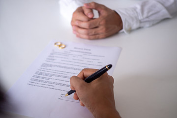 rings and person signing prenuptial agreement